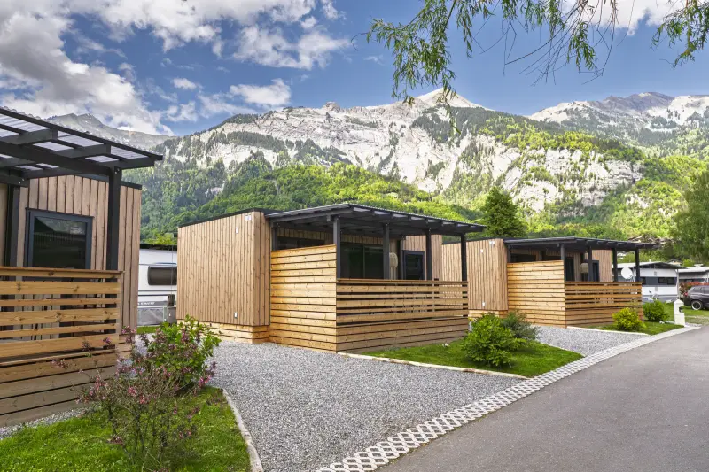 A row of wooden lodges below the mountains at Camping Aaregg