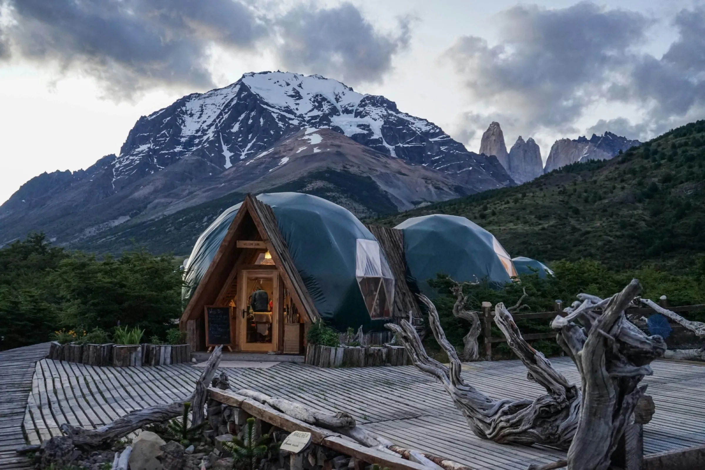 Glamping-Kuppelzelte vor verschneiten Bergen in der Abenddämmerung